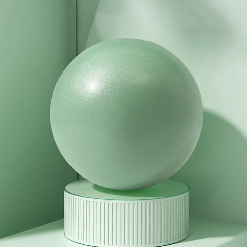 Green pilates ball on a cylindrical base against a green wall