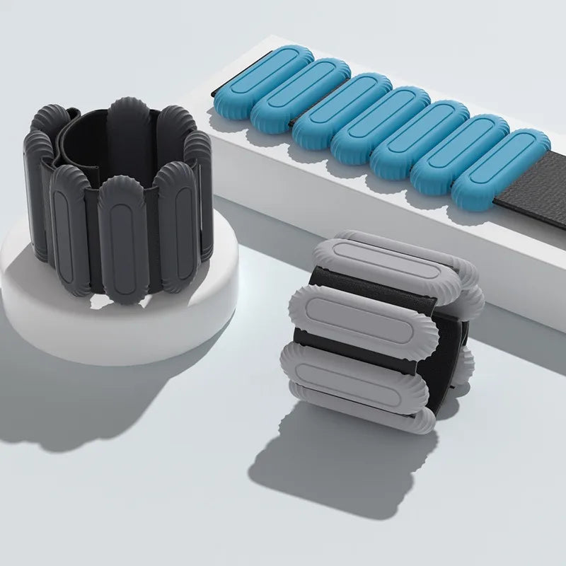Set of black, gray, and blue ankle and wrist weights on a light gray background