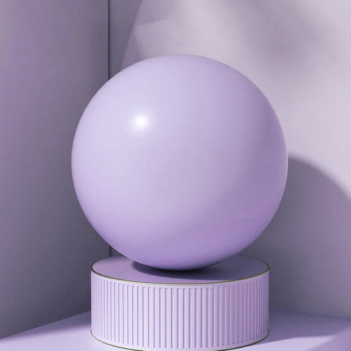 Purple pilates ball on a cylindrical stand against a gradient background