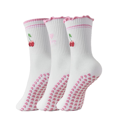 Three pairs of white socks with pink accents and cherry designs on a white background