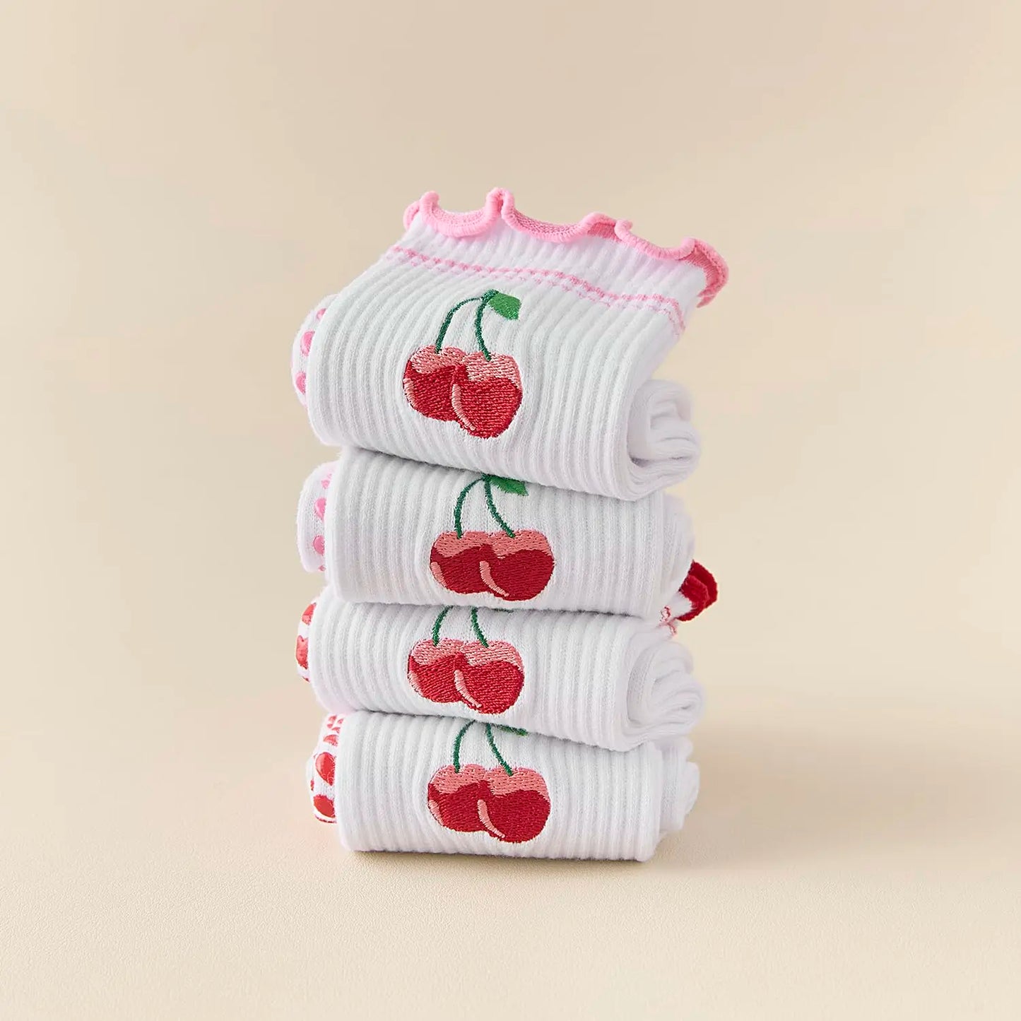 Stack of baby socks with cherry design on a beige background
