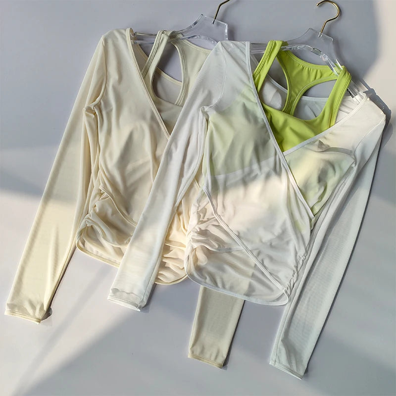 Set of light-colored athletic wrap top with built in crop top on hangers against a neutral background